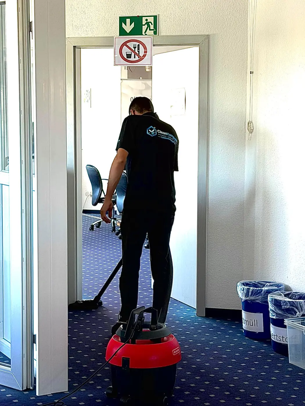 Cleankompass-Mitarbeiter saugt den Teppich in einem Büroflur